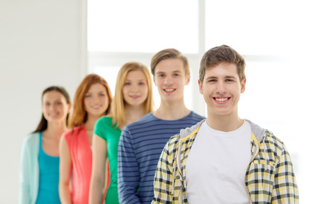 education and school concept - group of smiling students with teenage boy in frontの写真素材