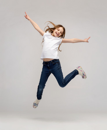 happiness, activity and child concept - smiling little girl jumpingの写真素材