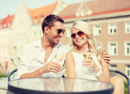 summer holidays and dating concept - smiling couple in sunglasses drinking wine in cafeの写真素材