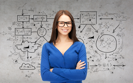 business and education concept - smiling businesswoman, teacher or student in glasses with big plan on the backの写真素材