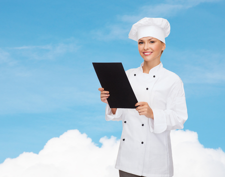 cooking, advertisement and food concept - smiling female chef, cook or baker with blank black menu paperの写真素材