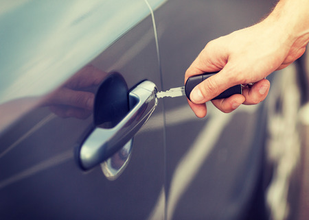 transportation and ownership concept - man with car key outsideの写真素材