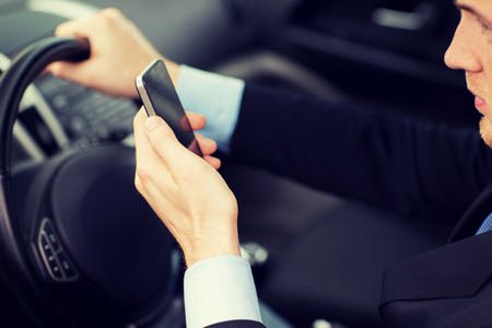transportation and vehicle concept - man using phone while driving the carの写真素材