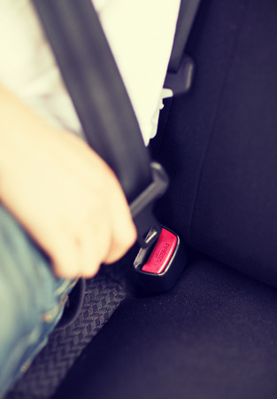 transportation and vehicle concept - man fastening seat belt in carの写真素材