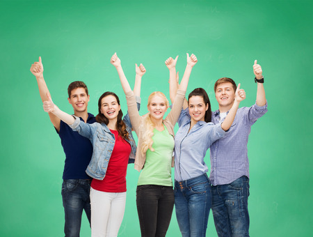 education and people concept - group of smiling students standing and showing thumbs upの写真素材