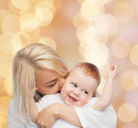 family, child and parenthood concept - happy mother kissing smiling babyの写真素材