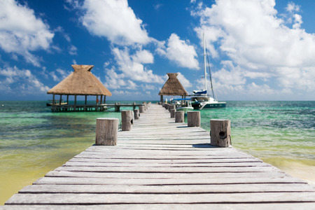 vacation, travel and sea concept - wooden pier with blue water around