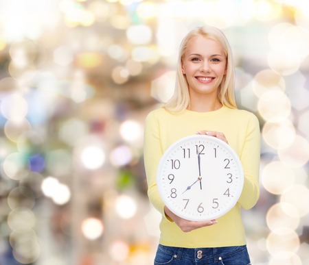 time, education and people concept - smiling young woman with wall clock showing 8