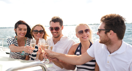 vacation, travel, sea, friendship and people concept - smiling friends with glasses of champagne on yachtの写真素材