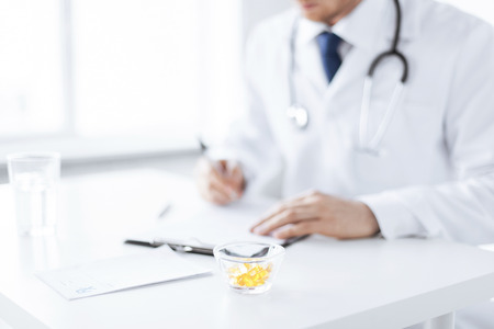 close up of male doctor writing prescription paper and capsulesの写真素材