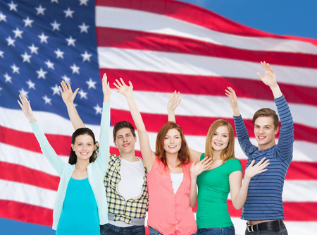 education and people concept - group of smiling students standing and waving handsの写真素材