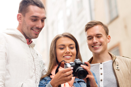 travel, vacation, technology and friendship concept - group of smiling friends with digital photocameraの写真素材