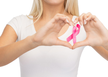 healthcare and medicine concept - young woman in blank white t-shirt with pink breast cancer awareness ribbon showing heart shapeの写真素材