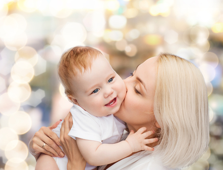 family, child and parenthood concept - happy mother kissing smiling babyの写真素材