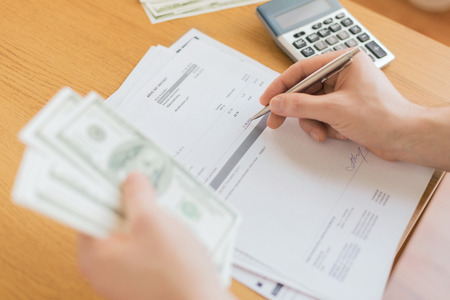 savings, finances, economy and home concept - close up of man with calculator counting money and...
