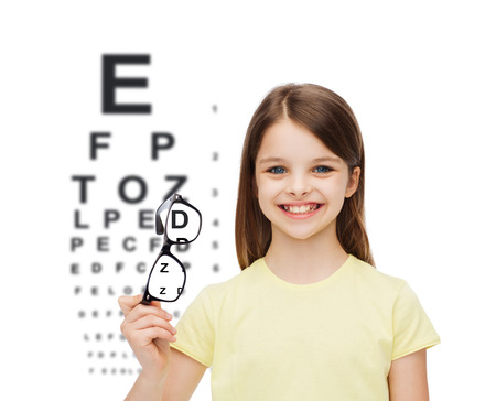 education, school and vision concept - smiling cute little girl holding black eyeglassesの写真素材