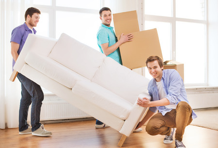 repair, furniture, decorating and home concept - smiling friends with sofa and cardboard boxesの写真素材