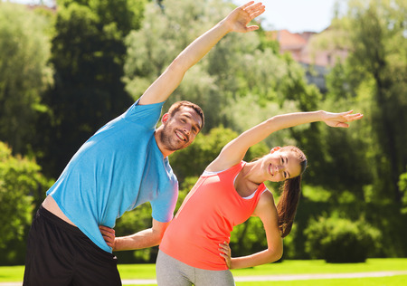 fitness, sport, training and lifestyle concept - smiling couple stretching outdoorsの写真素材