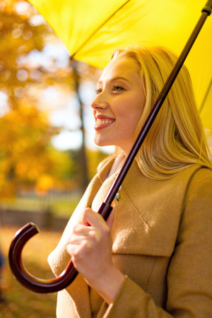 season, happiness and people concept - smiling woman with umbrella in autumn parkの写真素材