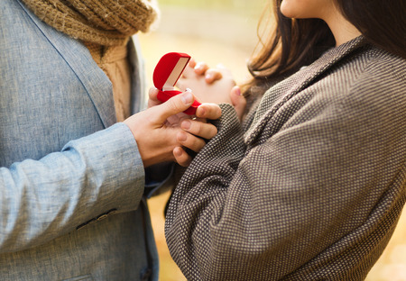 love, relationship, family and people concept - close up of couple with red gift box in autumn parkの写真素材
