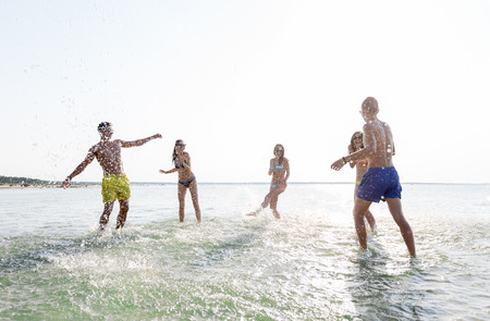 friendship, sea, summer vacation, holidays and people concept - group of happy friends having fun on summer beachの写真素材