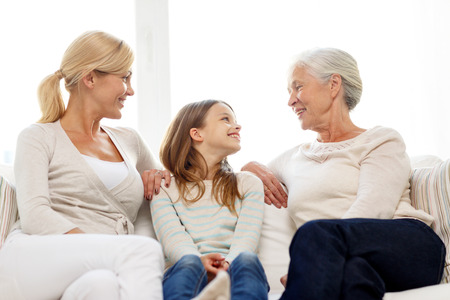 family, happiness, generation and people concept - smiling mother, daughter and grandmother sitting...