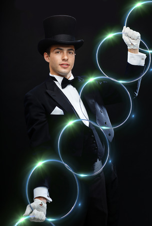 magic, performance, circus, show concept - magician in top hat showing trick with linking ringsの写真素材