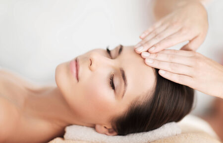 spa, resort, beauty and health concept - beautiful woman in spa salon getting face treatmentの写真素材