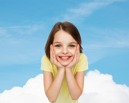 happiness and people concept - smiling little girl holding head over white backgroundの写真素材