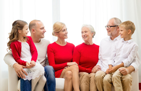 family, holidays, generation, christmas and people concept - smiling family sitting on couch at homeの写真素材