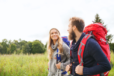 adventure, travel, tourism, hike and people concept - smiling couple walking with backpacks outdoors