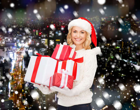 happiness, winter holidays, christmas and people concept - smiling young woman in santa helper hat...