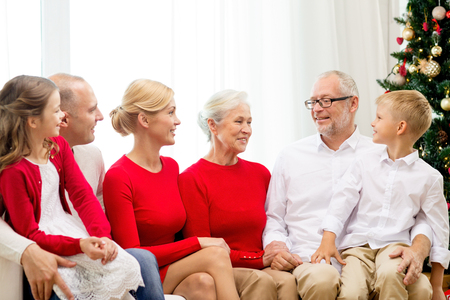 family, holidays, generation, christmas and people concept - smiling family sitting on couch at homeの写真素材