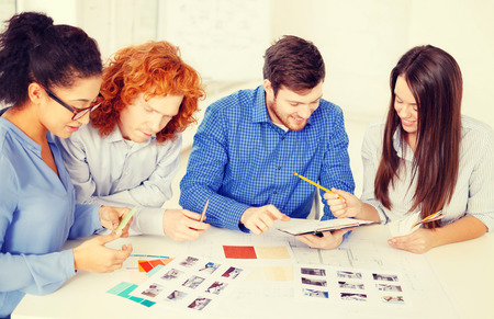 business, office, architecture and startup concept - smiling creative team with color samples and blueprint at officeの写真素材