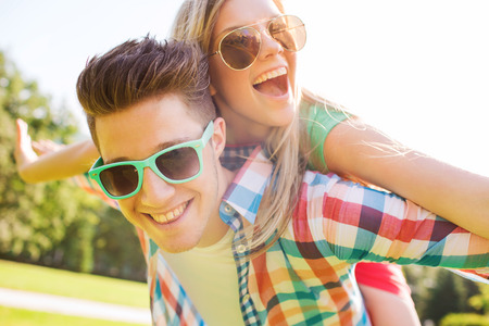 holidays, vacation, love and friendship concept - smiling teen couple in sunglasses having fun in summer park