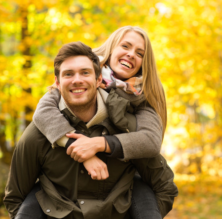 love, relationship, family and people concept - smiling couple having fun in autumn park