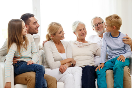 family, happiness, generation and people concept - happy family sitting on couch at home