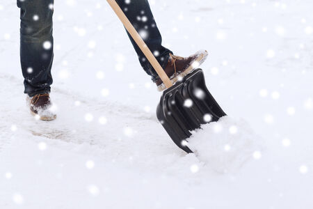 transportation, winter, people and vehicle concept - closeup of man digging snow with shovelの写真素材