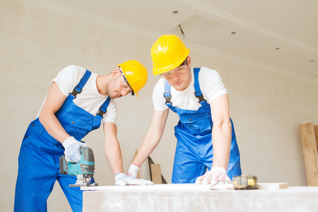 business, building, teamwork and people concept - group of smiling builders in hardhats with tools...