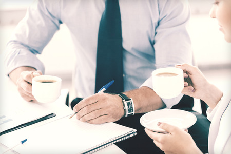 business, school and education concept - smiling businesswoman and businessman discussing something in officeの写真素材