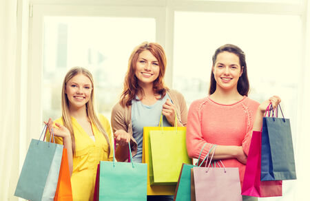 shopping and lifestyle concept - three smiling teenage girls with many shopping bags at homeの写真素材
