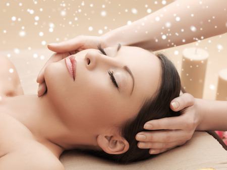 beauty, health, holidays, people and spa concept - beautiful woman in spa salon getting face or head massageの写真素材