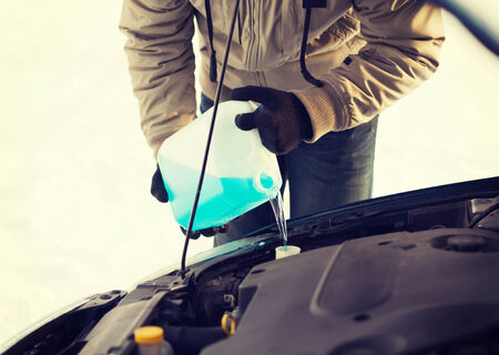 transportation, winter and vehicle concept - closeup of man pouring antifreeze into windscreen water tankの写真素材