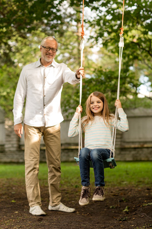  happy grandfather and  granddaughter swinging on teeterboard outdoorsの写真素材