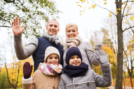family, childhood, season, gesture and people concept - happy family waving hands in autumn parkの写真素材