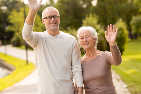 family, age, tourism, gesture and people concept - senior couple waving hands in city parkの写真素材