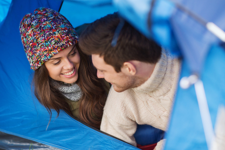 camping, travel, tourism, hike and people concept - smiling couple of tourists looking out from tentの写真素材