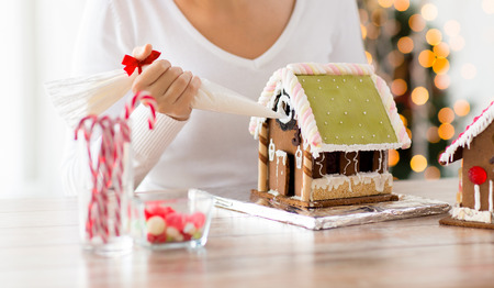 cooking, people, christmas and decoration concept - happy woman making gingerbread houses at homeの写真素材