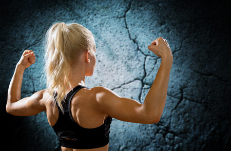 fitness, sport and people concept - sporty woman flexing and showing biceps form back