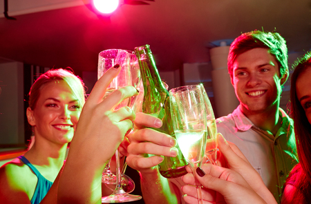 party, holidays, celebration, nightlife and people concept - smiling friends clinking glasses of champagne and beer in clubの写真素材